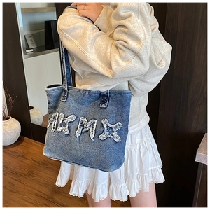 Blue washed denim tote bag featuring white frayed letter embroidery for a vintage look