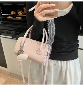 Detail of light pink crossbody bag with metal heart charm in a lifestyle kitchen setting