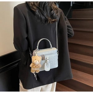Detail der hellblauen Box-Tasche mit Webstruktur und süßem Plüschbär-Anhänger