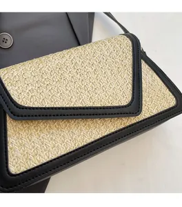 Close-up of woven straw shoulder bag featuring black PU contrast trim and fine texture