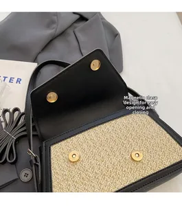 Detail of dual magnetic snap closure on straw woven crossbody bag with black leather trim