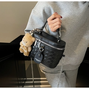 Detail der schwarzen gewebten Box-Tasche mit Silber-Zippern, Kette und Bärenanhänger