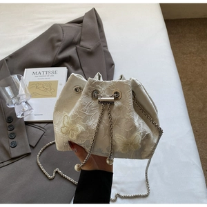 Detailed view of white floral lace bucket bag with 3D butterfly accents and chain strap