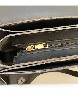 Detail view of the black leather shoulder bag interior featuring a smooth gold zipper pocket