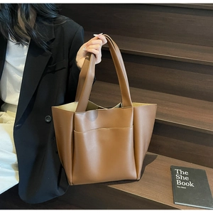 Detail of wide shoulder strap and front pocket on brown faux leather tote bag