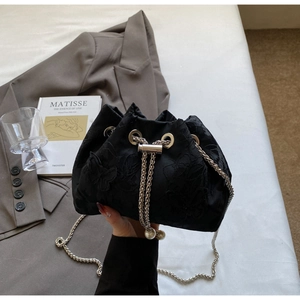Detail of black drawstring bucket bag with floral embroidery and pearl chain accents