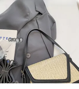 Detail view of rainbow woven straw handbag with black leather trim on a grey suit
