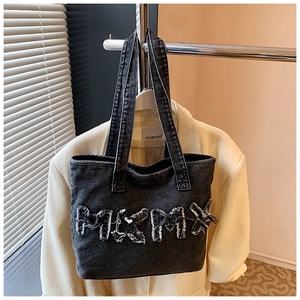 Close-up of black washed denim tote bag with frayed MIKMIX letter patch and texture