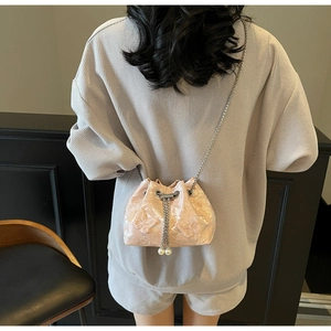 Detail of pink satin bucket bag featuring butterfly embroidery and pearl drawstring