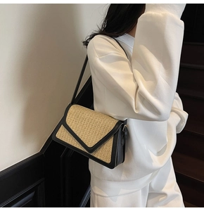 Close-up of rainbow straw woven shoulder bag with black leather trim on model