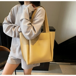 Close-up of beige large tote bag in matte leather featuring a functional front flat pocket