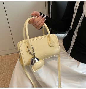 Detail of yellow faux leather handbag with silver heart charm and clearox logo engraving