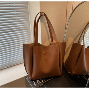 Detail shot of brown leather tote bag with front pocket in natural window light