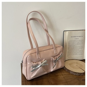 Detail of pink glossy shoulder bag featuring silver metallic bows on front pockets