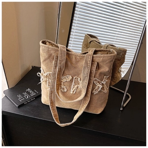 Detail view of khaki washed canvas tote bag with frayed letter design and dual handles