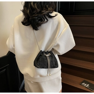 Detail of black butterfly embroidery drawstring bucket bag with silver metal chain strap