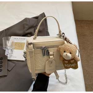 Detail der cremefarbenen Web-Box-Tasche mit Reißverschlüssen, Kette und Bären-Anhänger