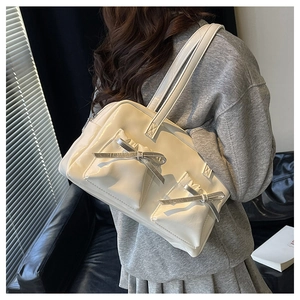 Detail of cream shoulder bag with bow-decorated pockets and shiny leather finish