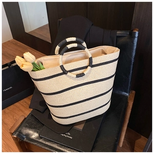 Detail of striped straw tote bag featuring round handles and textured weave