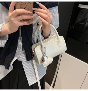 Detail of white rectangle handbag with heart charm and detachable shoulder strap