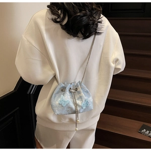 Close-up of light blue satin bucket bag with 3D butterfly appliques and pearl charms