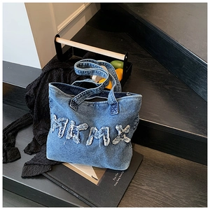 Detail of vintage washed denim tote bag with distressed MKMX lettering and frayed edges