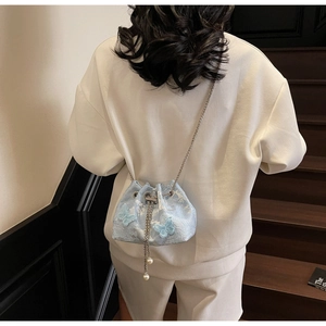 Detail of light blue lace bucket bag with 3D butterflies and pearl fringe charm
