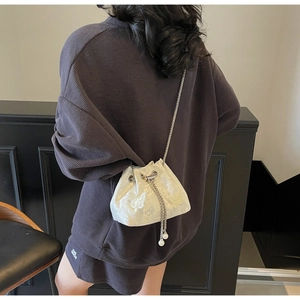 Close-up of white satin bucket bag featuring butterfly patterns and pearl drawstrings
