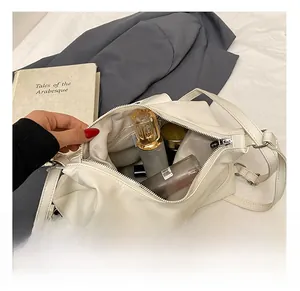 Spacious interior of white leather tote bag showing storage for cosmetics and perfume