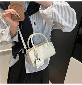 Minimalist white leather bag with heart charm shown in a mirror selfie for size reference