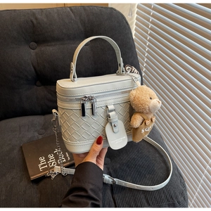 Detail der gewebten Leder-Box-Tasche in Minzgrün mit Metallkette und Teddy-Anhänger