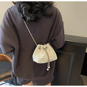 Detail of white butterfly embroidery bucket bag with silver chain and pearl drawstring