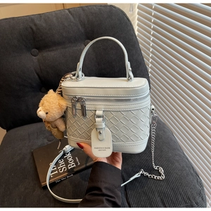 Detail der hellblauen gewebten Lederhandtasche mit Silberkette und Teddybär-Anhänger