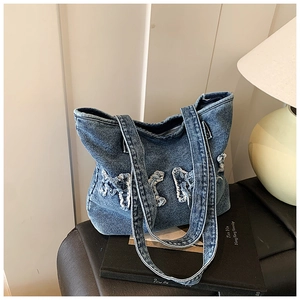 Detail of blue denim tote bag featuring vintage washed fabric and frayed bow appliques