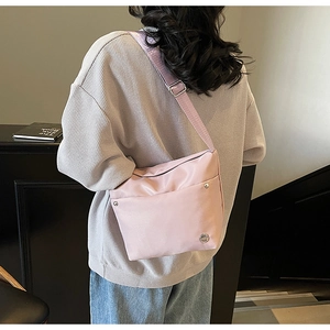 Gros plan du sac seau en nylon rose avec bandoulière réglable et logo sur mannequin