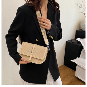 Detailed view of beige woven crossbody bag with embroidered jacquard shoulder strap
