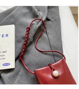 Detail of dark red mini crossbody bag with pearl buckle and braided shoulder strap