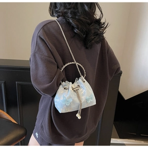 Detail of light blue bucket bag with floral embroidery and silver ring handle on model