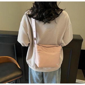 Gros plan d'un sac seau en nylon vieux rose porté en bandoulière dans un décor moderne