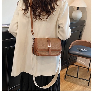 Close-up of vintage brown crossbody bag with woven texture flap and metallic lock