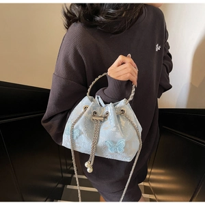 Detail of light blue bucket bag with jacquard fabric, floral patterns, and butterfly accents