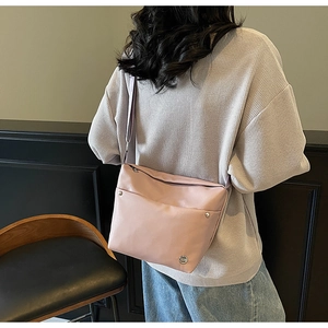 Vue de dos d'une femme portant le sac seau en nylon rose clair avec bandoulière