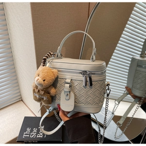 Detail der geflochtenen mintgrünen Box-Tasche mit Silberkette und Teddybär-Anhänger