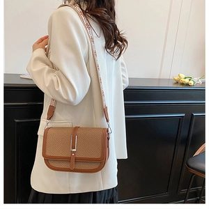 Side view of vintage brown crossbody bag with wide patterned strap on model