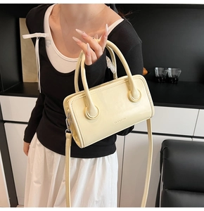 Detail shot of the cream yellow leather handbag featuring twin handles and embossed logo