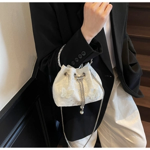 Detail of white butterfly embroidery and pearl drawstring on a stylish bucket bag
