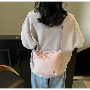 Vue détaillée d'un sac bandoulière en nylon rose clair avec sangle large réglable