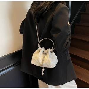 Detail of white drawstring bucket bag with floral embroidery and pearl accents