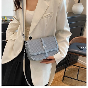 Detail of light blue crossbody bag with mesh texture and square metal buckle shown on model