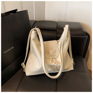 Close-up of beige leather tote bag featuring unique double star hardware and silver buckle